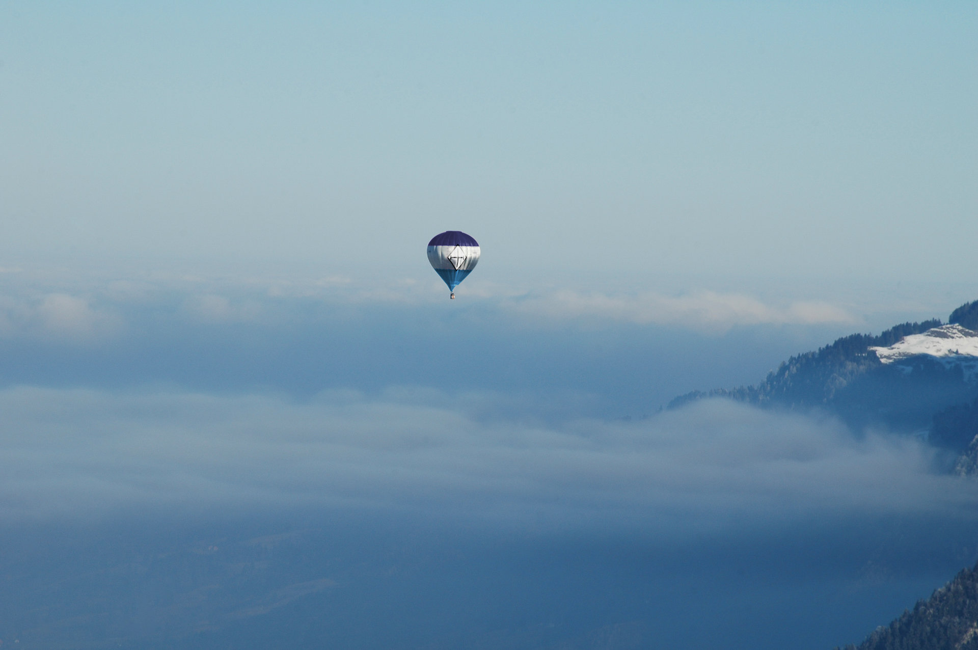 Hot air balloon with Upadaria flag pattern floats about misty mountains